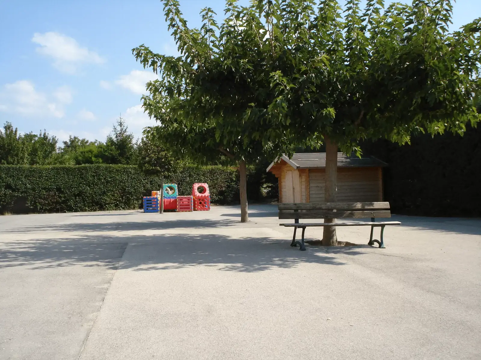 La cour de l'école, la cabane et les bancs sous les arbres