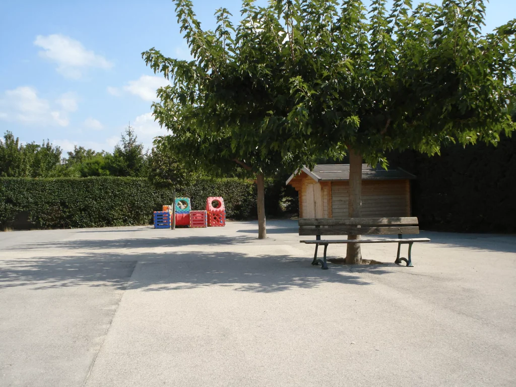 La cour de l'école, la cabane et les bancs sous les arbres